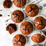 Chocolademuffins op een stuk krantenpapier met een verkruimelde muffin aan de zijkant