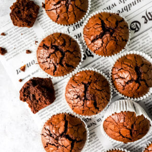 Chocolademuffins op een stuk krantenpapier met een verkruimelde muffin aan de zijkant