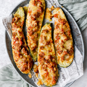 Bovenaanzicht van gehalveerde courgettes die opgevuld zijn met spaghettisaus en lekker veel kaas die goudbruin gebakken werd in de oven