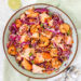 bovenaanzicht van een grote kom met een salade van dun gesneden rode kool, gebakken scampi's en zalm en quinoa en wortel. Afgewerkt met sesamzaadjes