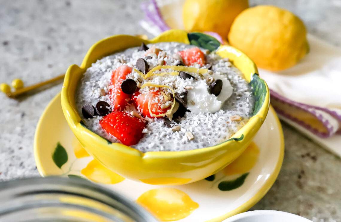Bloemvormige gele kom met romige chiapudding. Afgewerkt met aardbeien, chocolate chips, kokosrasp en citroenzeste