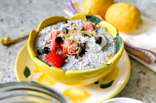 Bloemvormige gele kom met romige chiapudding. Afgewerkt met aardbeien, chocolate chips, kokosrasp en citroenzeste
