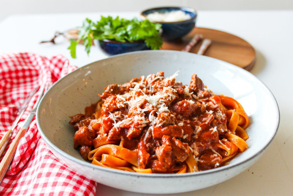 Een bord met tagliatelle met ragout van everzwijn afgewerkt met Parmezaanse kaas
