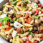 Grote kom pastasalade met spirelli, minigehaktballetjes, parmezaan, mozzarella, kerstomaatjes en heel veel basilicum.